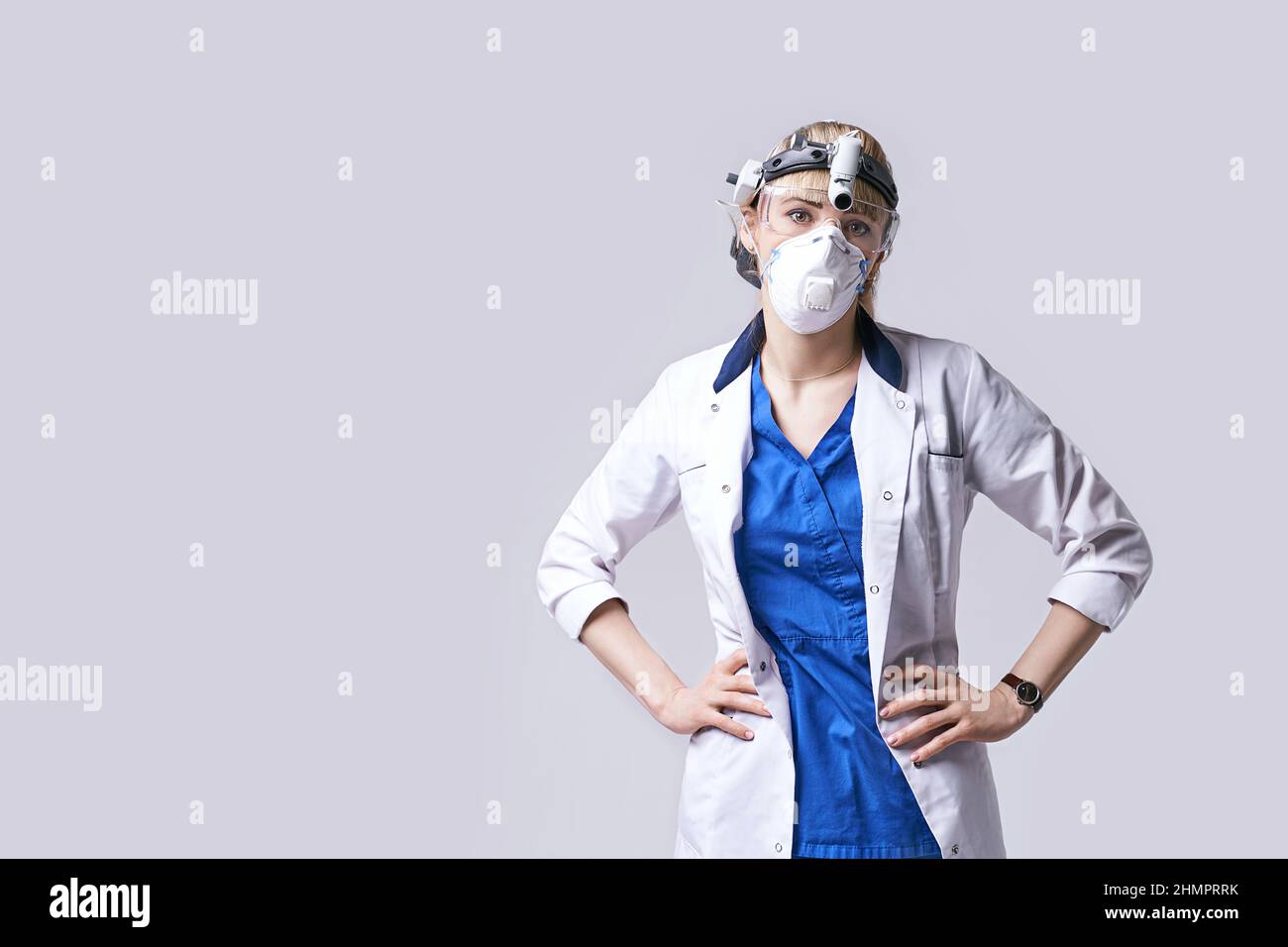 Medico di fiducia che indossa lanterna chirurgica per la testa del faro, maschera protettiva per il viso e occhiali. Ritratto di otolaringologo femminile o testa e collo Foto Stock