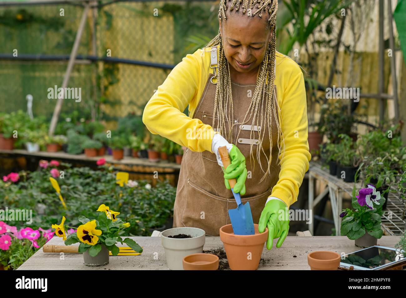 Donna africana felice adulto che prepara i fiori nel giardino della stanza dei bambini - concetto verde di primavera Foto Stock