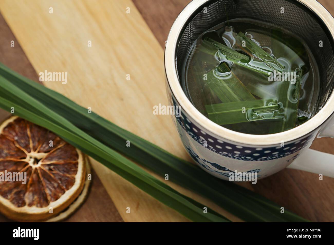 Goiânia, Goias, Brasile – 11 febbraio 2022: Una tazza di tè, con foglie di citronella e fette d'arancia disidratate, su una superficie di legno. Foto Stock