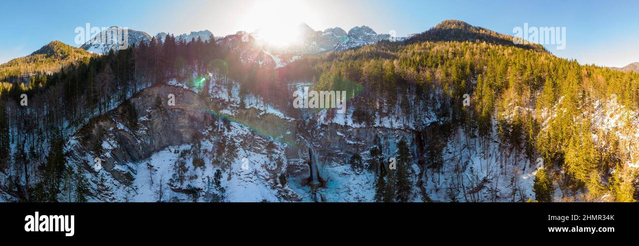 Spettacolare panorama montano con cascata che cade attraverso la sporgenza della foresta. Foto Stock