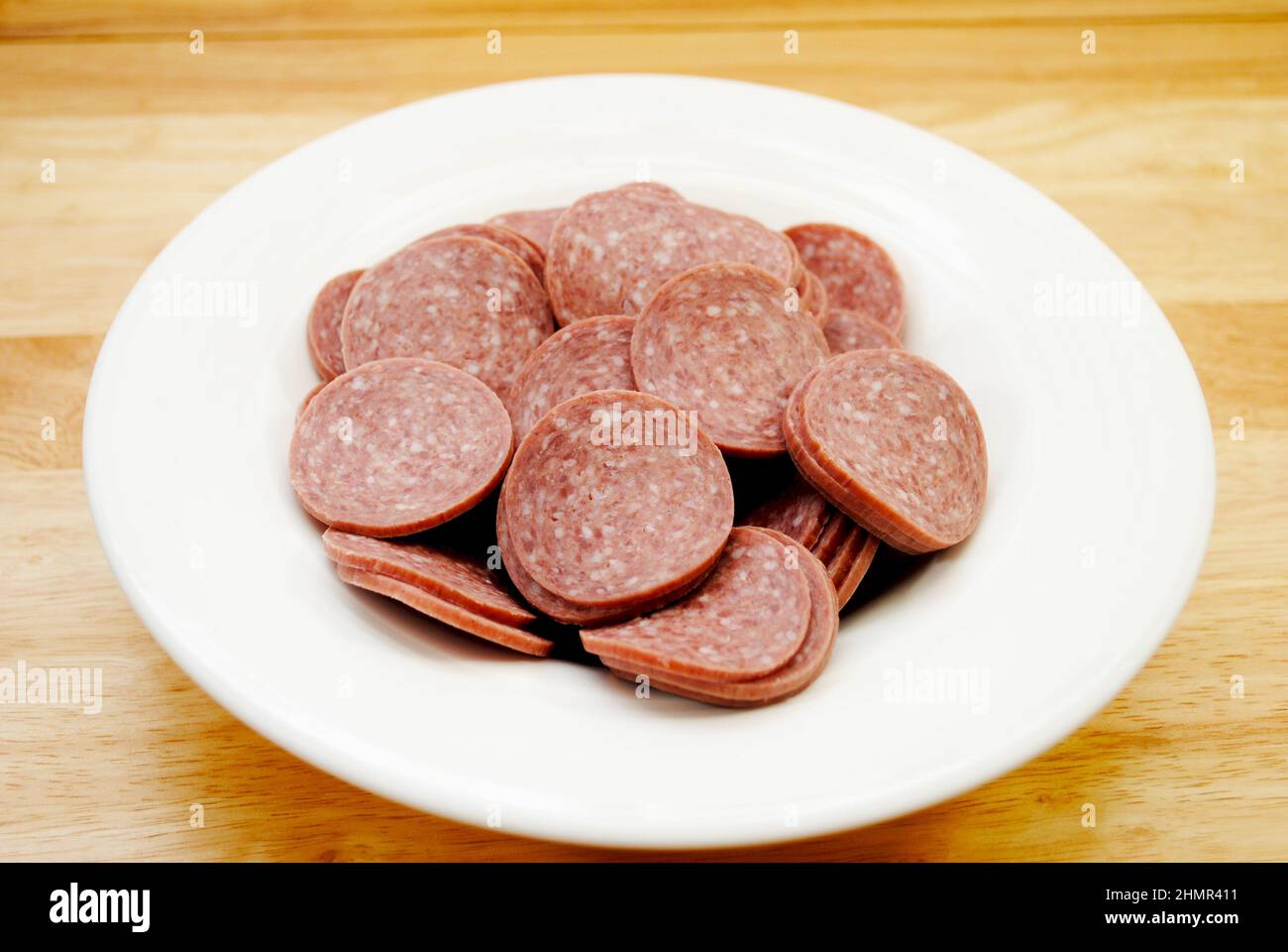 Fette di salame duro in un recipiente bianco Foto Stock