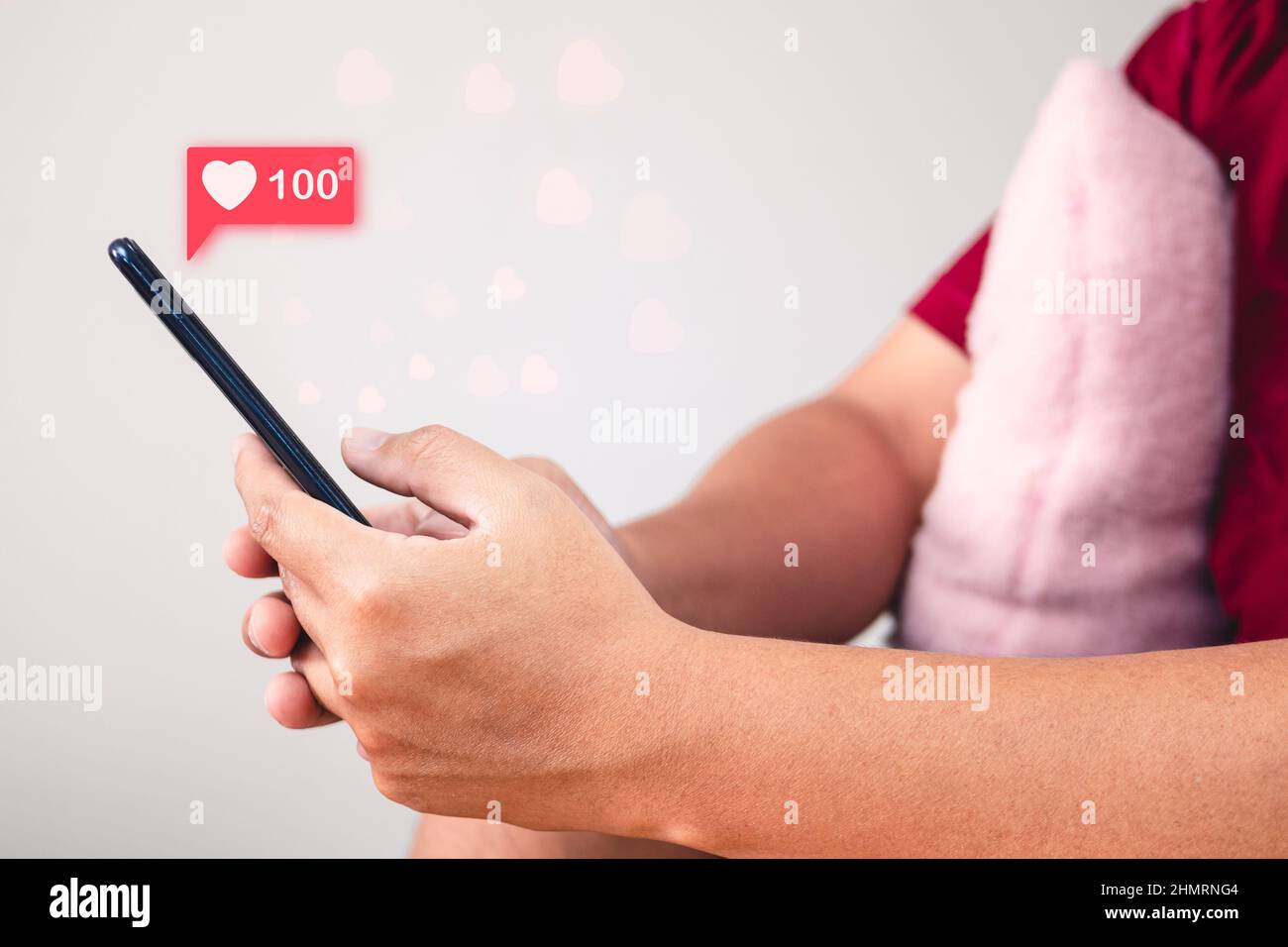 Concetto di San Valentino. L'uomo usa il segno della mano per dare e ricevere l'amore attraverso uno smartphone. Effetto visivo della forma del cuore. Vista laterale. Foto Stock