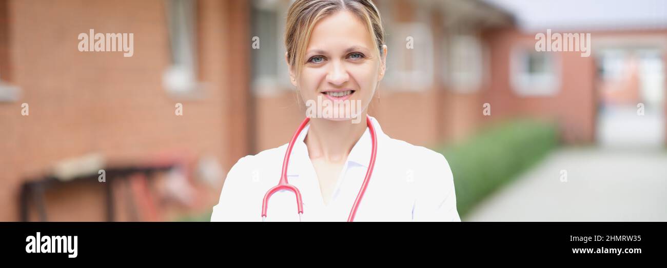 Ritratto di una donna sorridente medico con le braccia ripiegate sulla strada Foto Stock