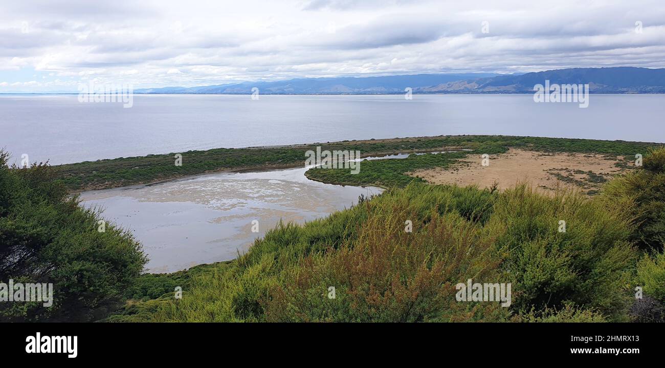 Sull'Isola di Kapiti, la Laguna di Okupe si affaccia sull'Isola Nord, Nuova Zelanda. Scena di sepolture guerrieri Maori e canoa affondando dopo 19th secolo battaglia tribale. Foto Stock