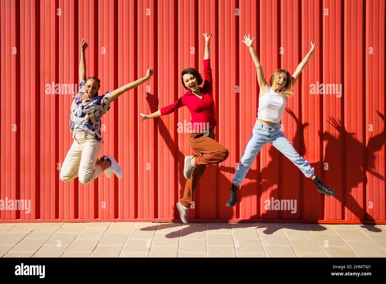 Allegro diverse donne che saltano vicino al muro Foto Stock