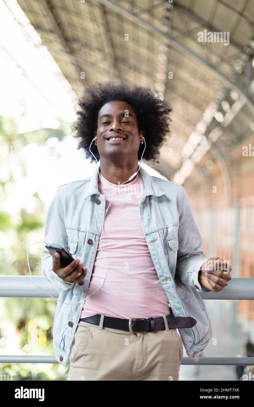 Felice uomo afroamericano che gode la musica dal suo telefono. Emozione positiva, stile di vita e felicità. Foto Stock