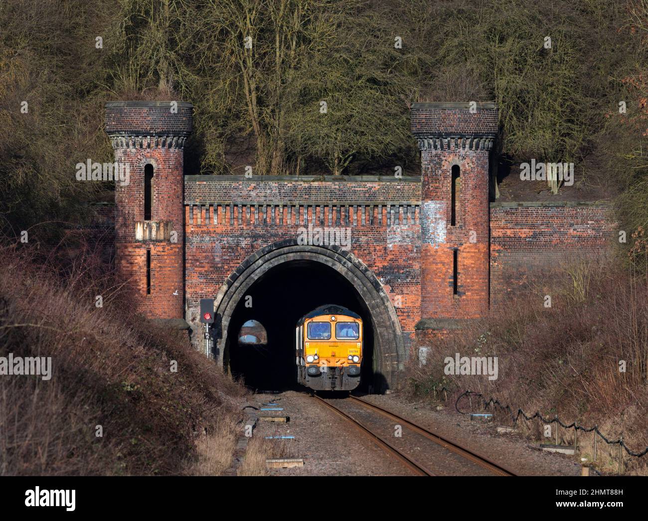 2 GB Railnight classe 66 locomotive lasciando il tunnel ornato Kirton Lindsey sulla linea Brigg, Lincolnshire, mentre gira un motore leggero Foto Stock