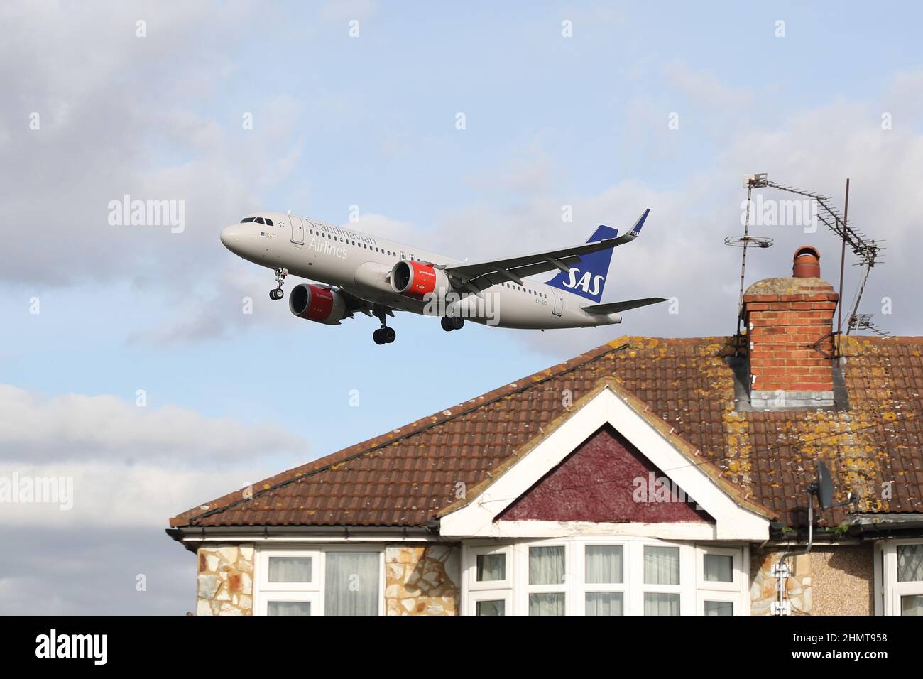 Un Airbus A320neo della Scandinavian Airlines si avvicina all'aeroporto di Heathrow volando in basso sopra i tetti delle case in Myrtle Avenue, Londra, Regno Unito Foto Stock