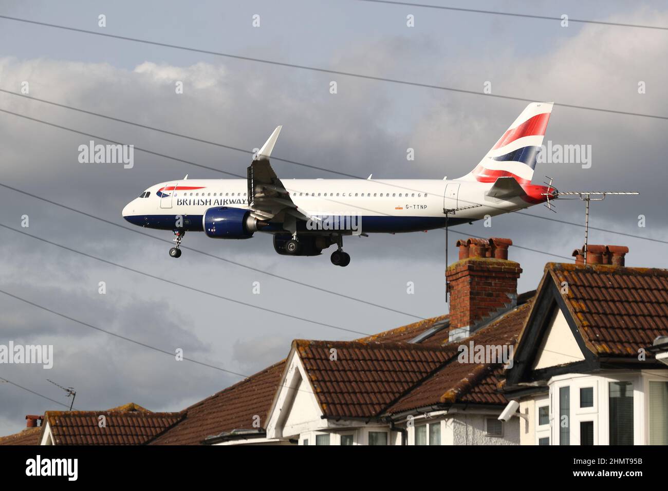 Un British Airways Airbus A320neo G-TTNP si avvicina all'aeroporto di Heathrow volando in basso sopra i tetti delle case in Myrtle Avenue, Londra, Regno Unito Foto Stock