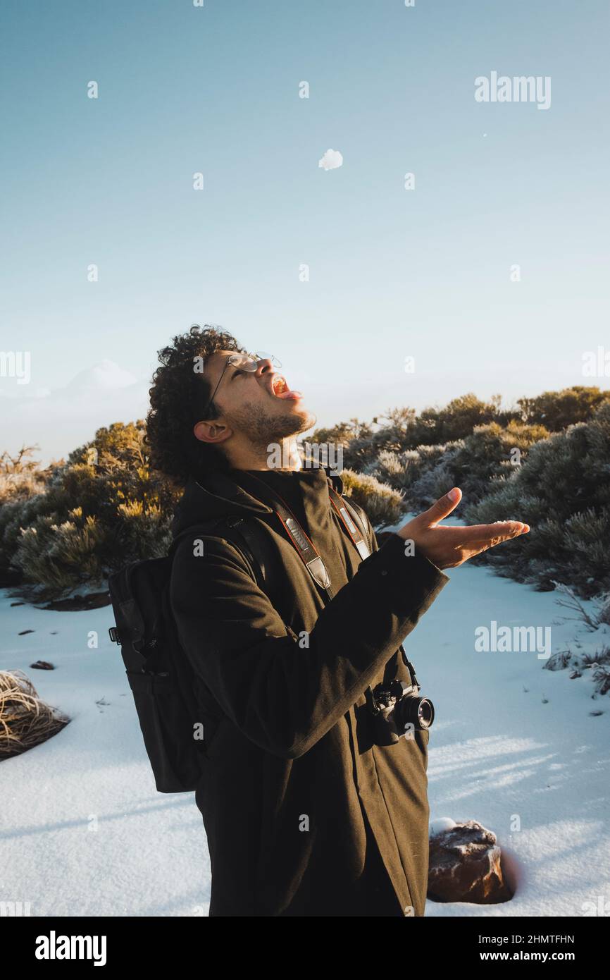 Giovane uomo nero mangiare neve e divertirsi Foto Stock