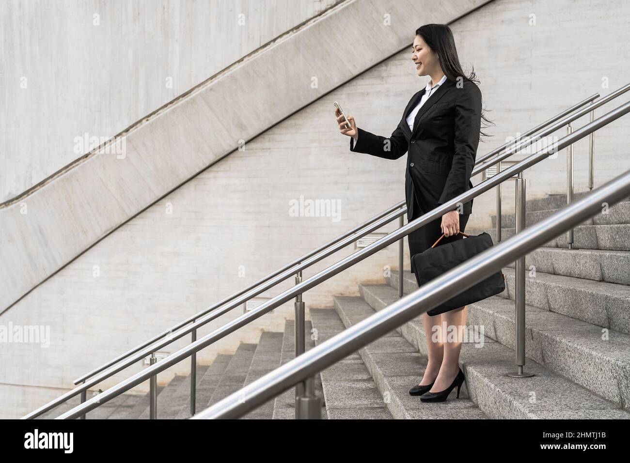 Donna d'affari asiatica che usa lo smartphone mobile fuori dall'ufficio - concetto di imprenditorialità Foto Stock