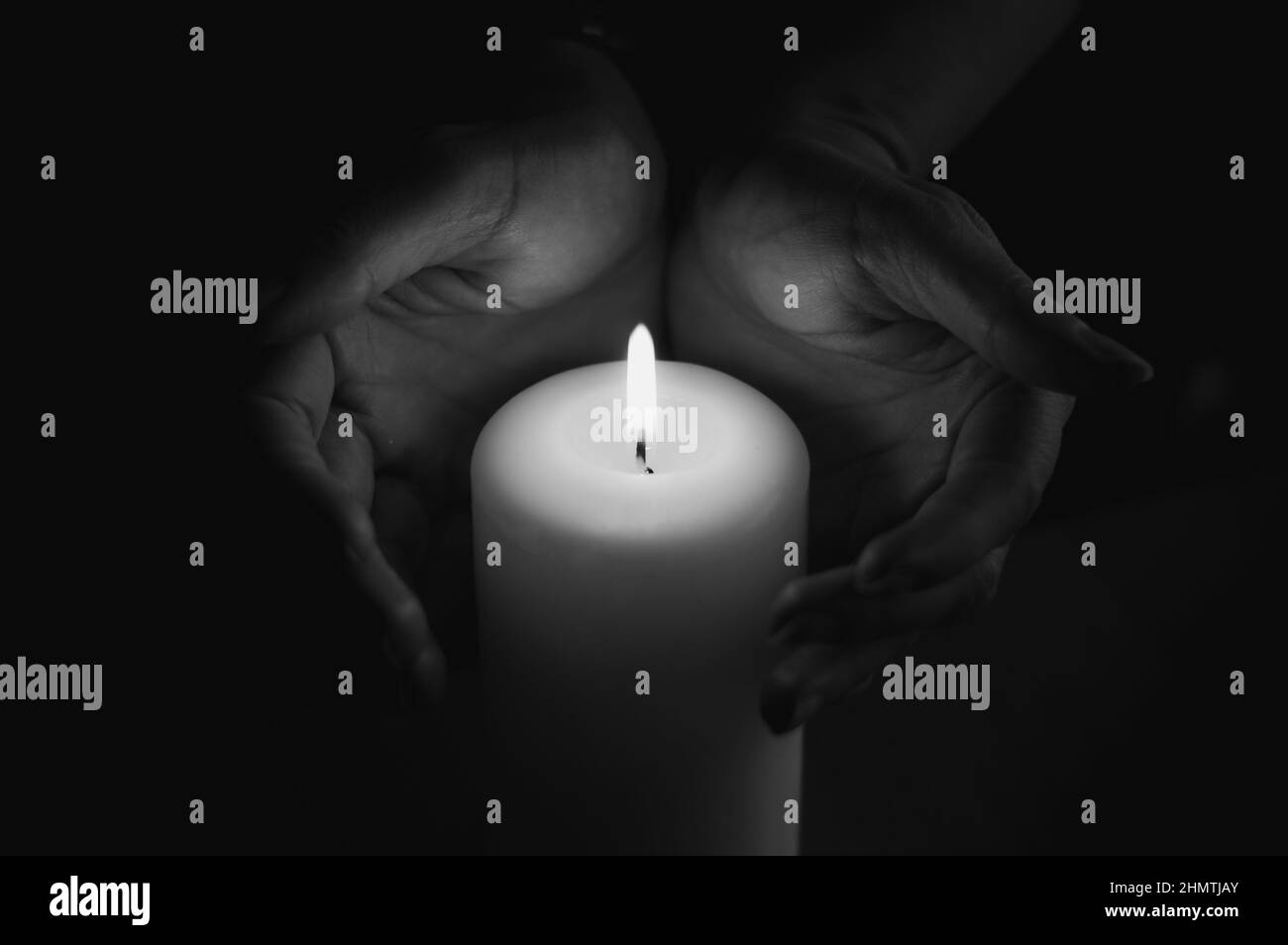 Le mani si riscaldano alla fiamma della candela Foto Stock