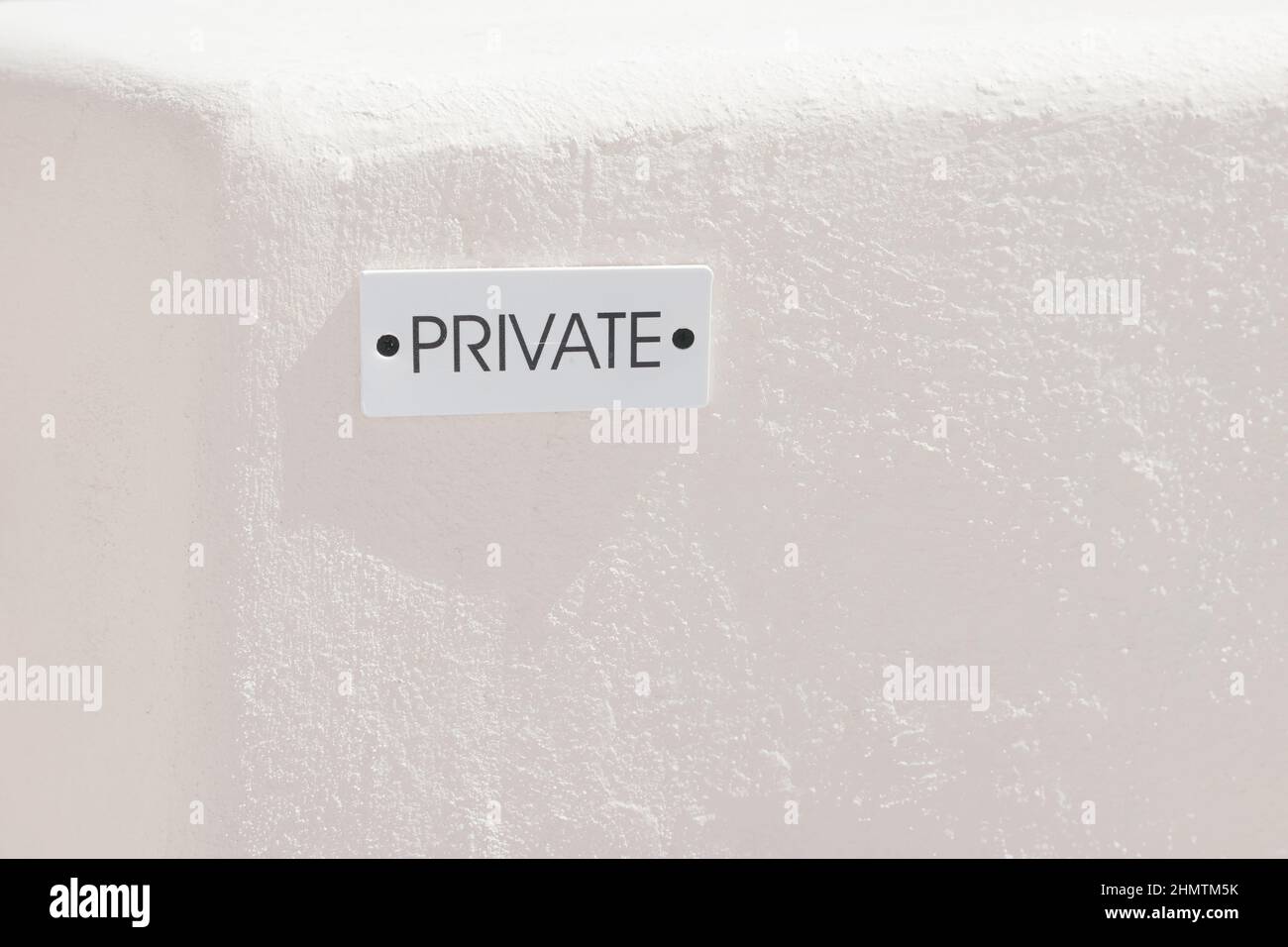 Segno bianco con le parole 'private' in inglese su muro di pietra beige, posto privato sull'isola Santorini, Oia, Grecia. Non è consentito entrare. Copia spac Foto Stock