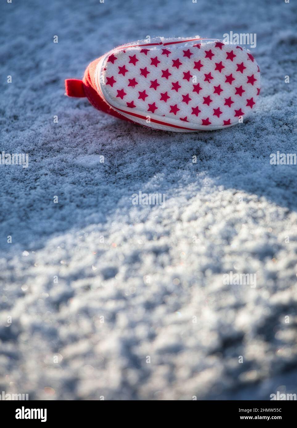 Stelle sulla suola del trainer rosso per bambini abbandonate nella neve. Concetto di rapimento, perso, pericolo, intrighi, curiosità, crimine, mistero Foto Stock