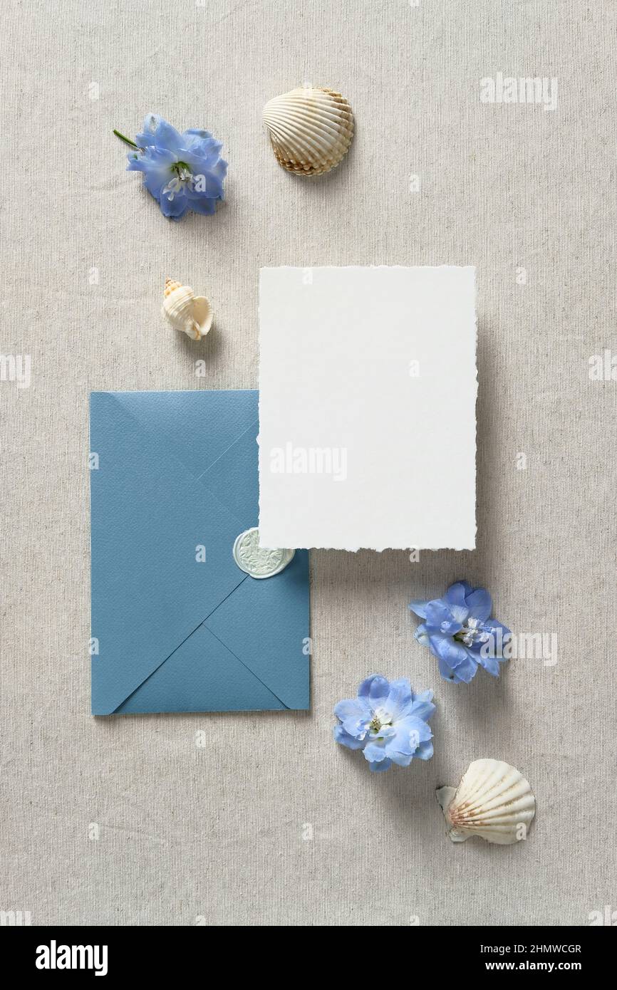 Set di carta di invito per matrimoni e busta blu con conchiglie su tavolo beige. Salvare il design in stile mare data. Concetto di matrimonio nautico. Foto Stock