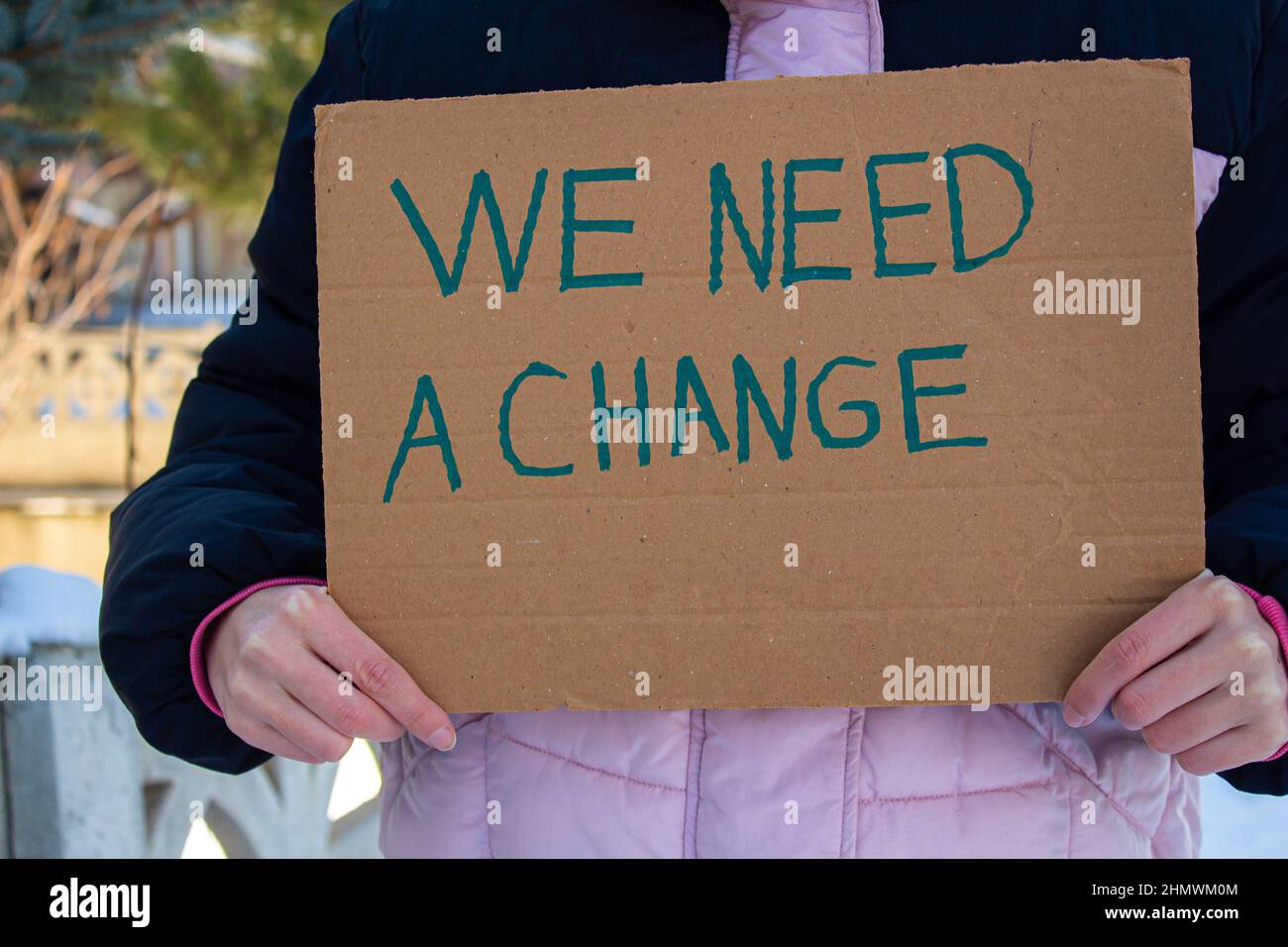 Tenere a mano la scatola di cartone con abbiamo bisogno di un testo di cambiamento. Donna che protesta contro l'inquinamento ambientale, la disuguaglianza, il razzismo o qualcos'altro. Foto Stock