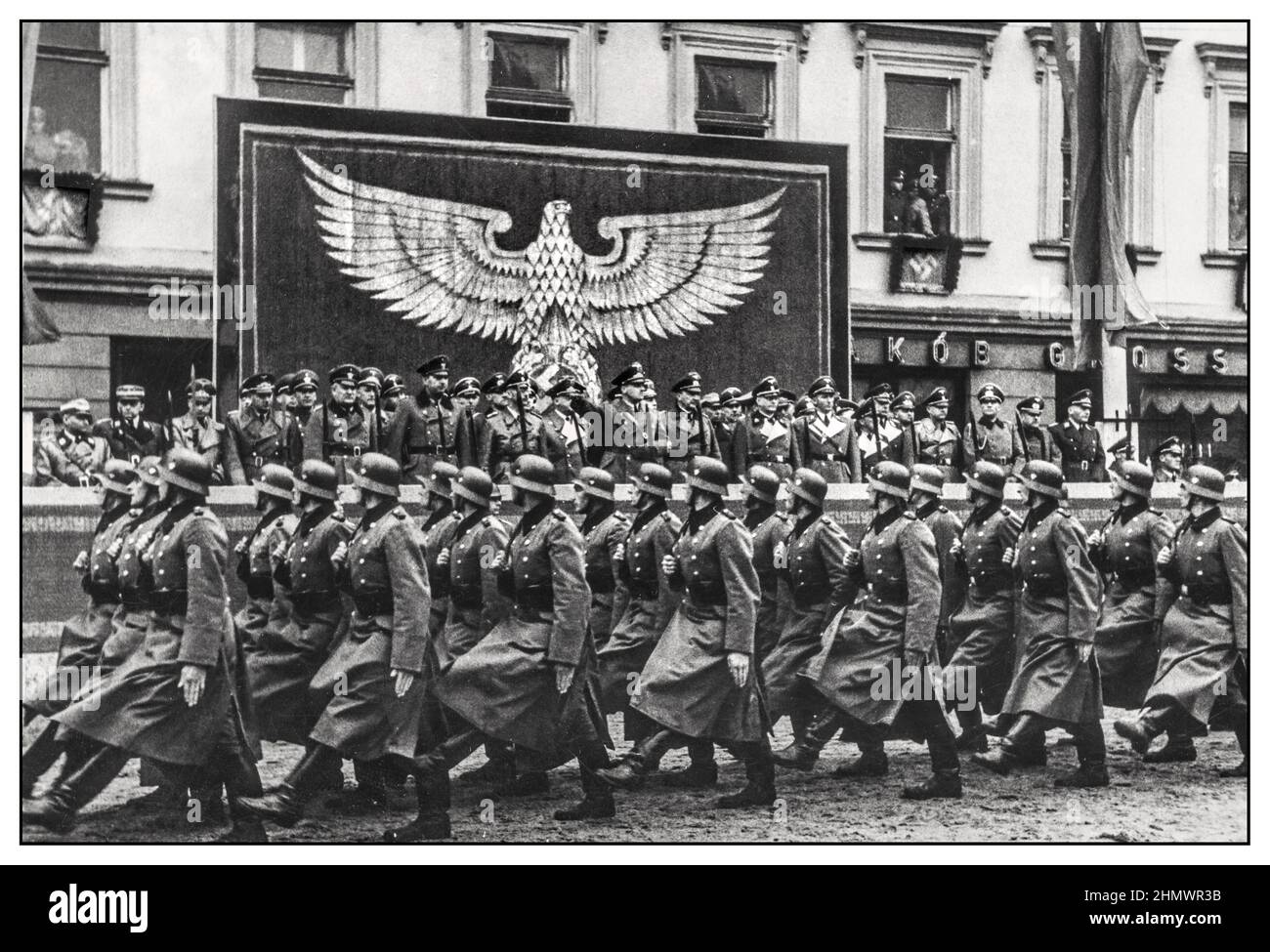 WW2 occupazione nazista della Polonia marzo passata sfilata con ufficiali nazisti di alto rango che prendono il saluto della polizia nazista goose che passa vicino. Sfilata di polizia di fronte al governatore Hans Frank in pl. Adolf Hitler (piazza principale) a Cracovia nel primo anniversario dell'istituzione del Governo Generale. Sullo sfondo, la tribuna onoraria. Sullo stand si possono vedere, amonstg altri: Hans Frank, Heinrich Himmler, il generale Kurt von Gienanth e otto von Wachter. 1940-10-26 Foto Stock