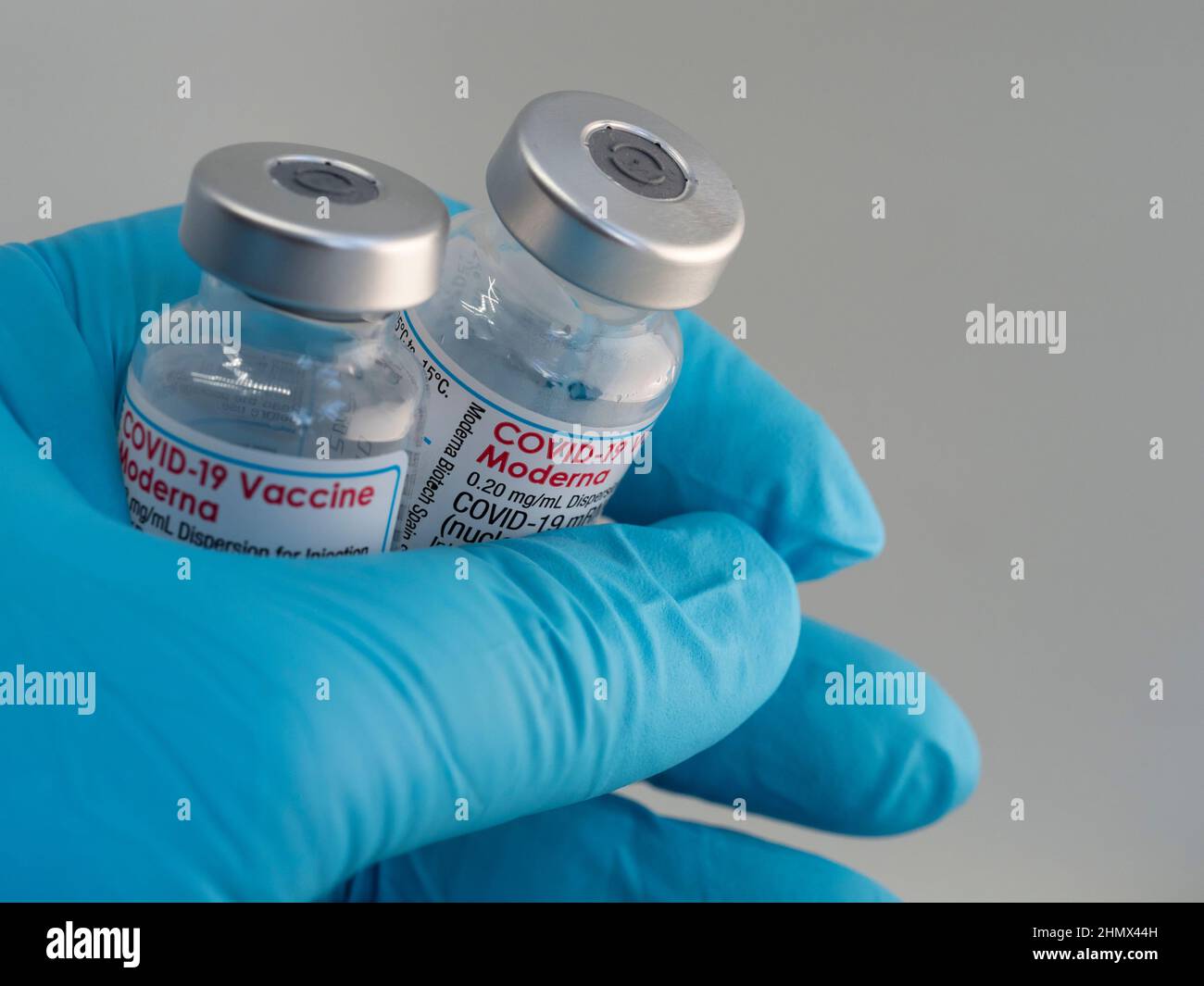 Primo piano un flaconcino con il vaccino Moderna Covid-19, tenuto da una mano in guanti medici Foto Stock
