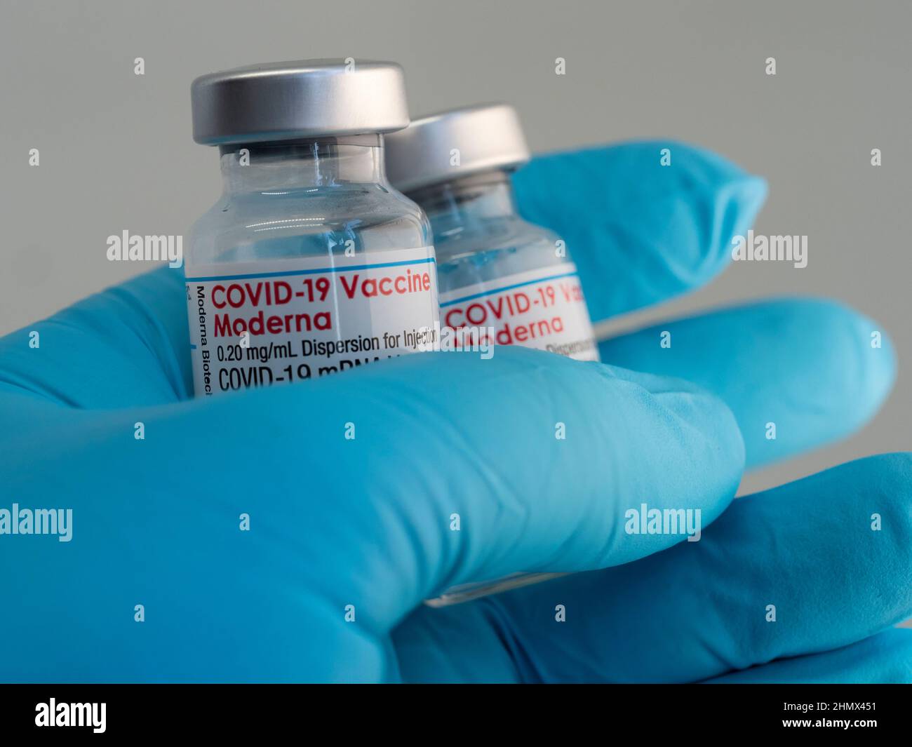 Primo piano un flaconcino con il vaccino Moderna Covid-19, tenuto da una mano in guanti medici Foto Stock