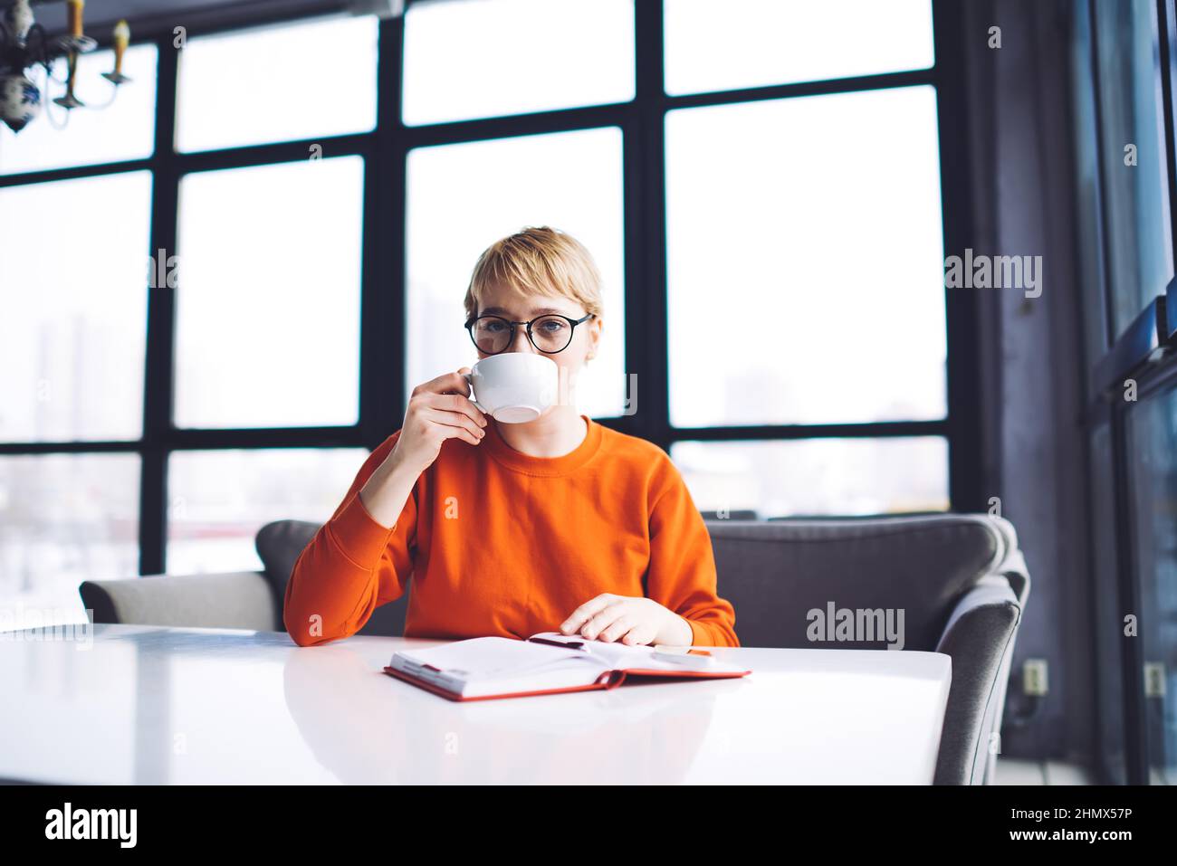 Donna che beve caffè nella moderna caffetteria Foto Stock