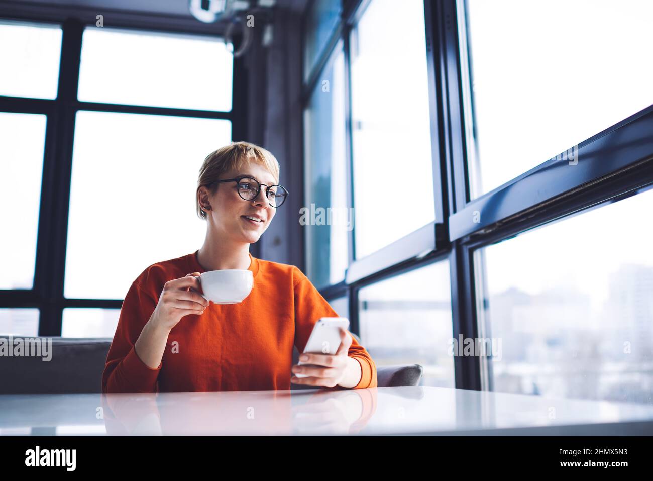 Donna sorridente con telefono cellulare godersi il caffè Foto Stock