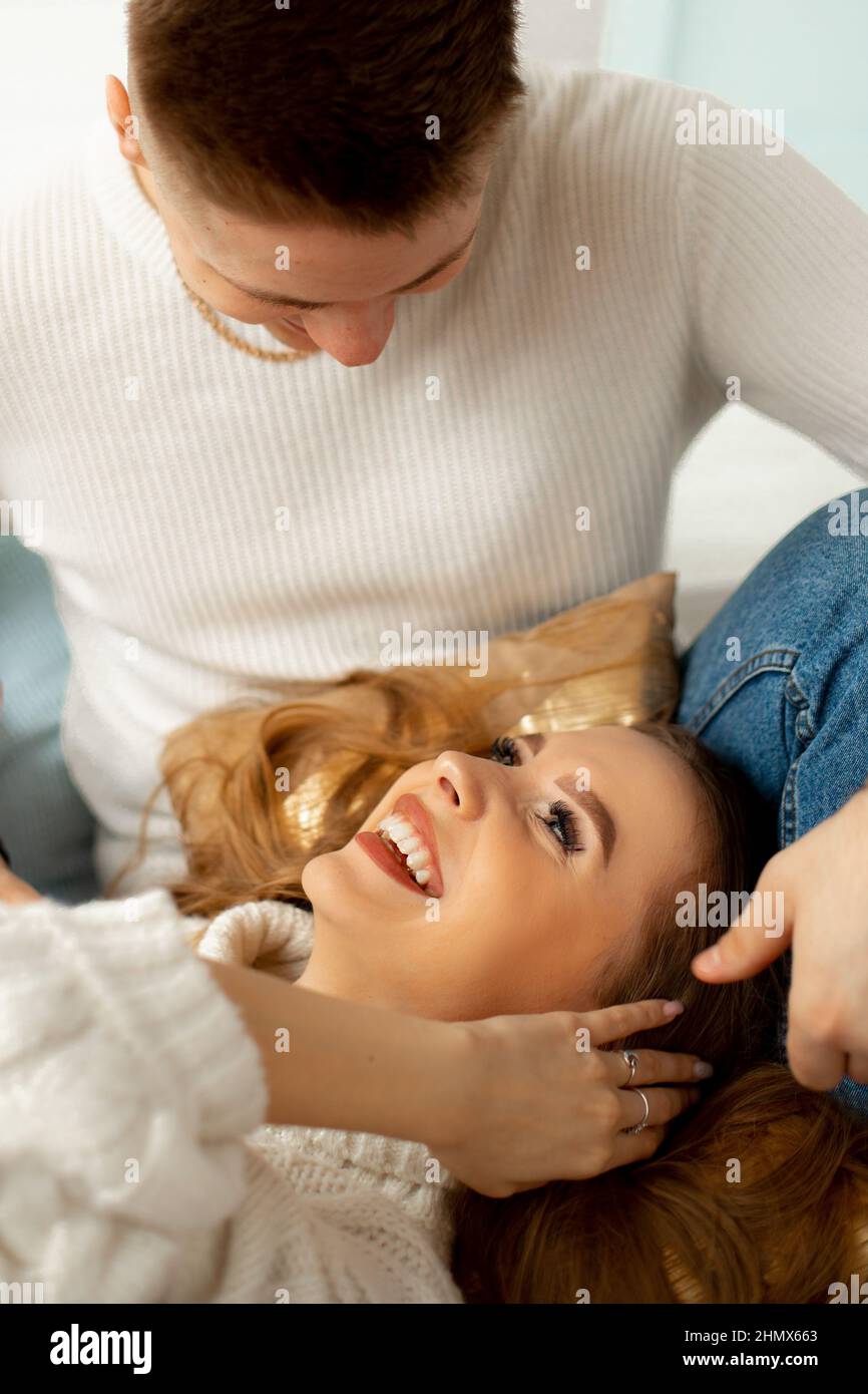 Il giovane uomo in maglia bianca si chinò sul suo amato, giacendo in grembo. La ragazza felice sorride felicemente alla sua amica. Data romantica. Meraviglioso Foto Stock