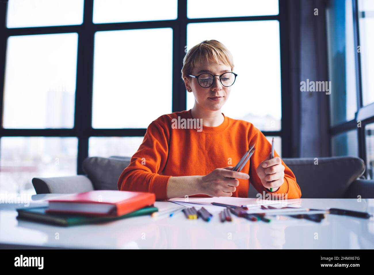 Donna felice con matite in ambiente di lavoro moderno Foto Stock