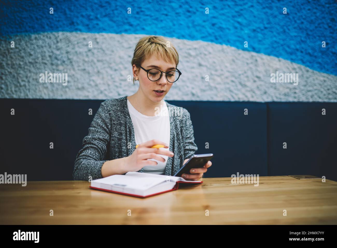 Donna pensiva che naviga smartphone durante il lavoro Foto Stock