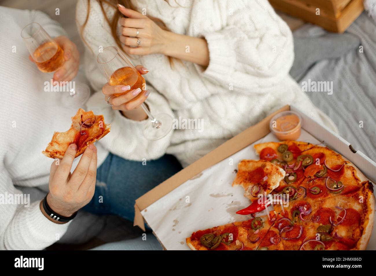 Deliziosa pizza fragrante e vino in bicchieri di vetro dà piacere a coppia in amore in una romantica data. Piacere di mangiare. Ottimo appetito Foto Stock