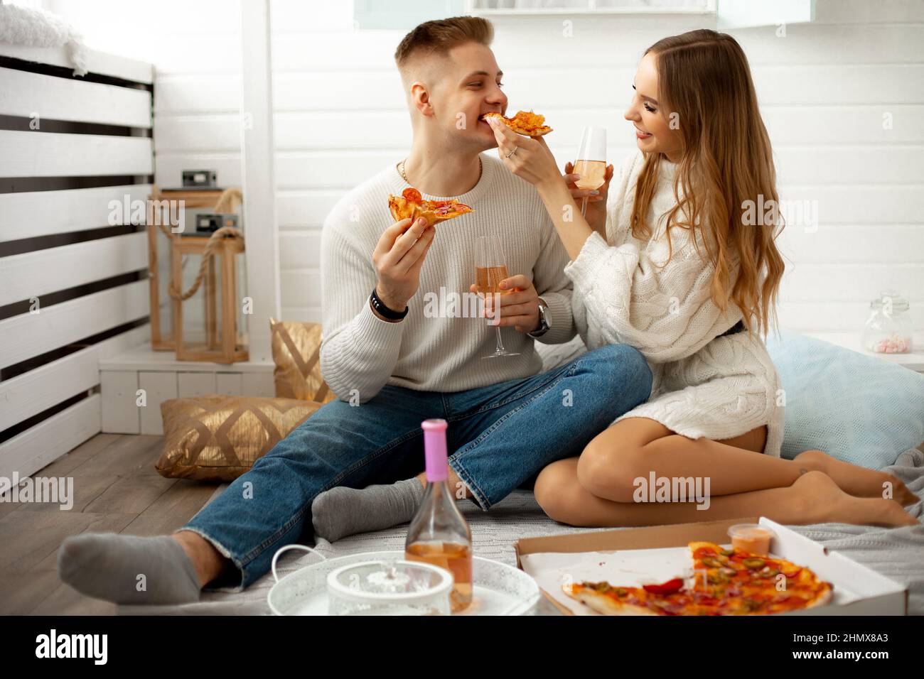 Una giovane coppia carina ama pranzare insieme , si nutrono scherzosamente a vicenda la pizza . Data a casa. Momenti meravigliosi. Relazioni d'amore. Romanticismo in Foto Stock