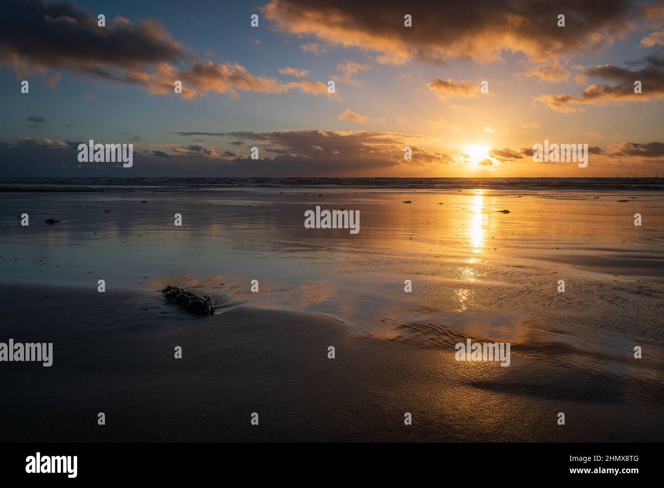 Tramonto con nuvole e riflessi illuminati, a Sandy Gap, spiaggia di Walney, isola di Walney, barrow in furness, Cumbria, Regno Unito il 4th febbraio 2022 Foto Stock