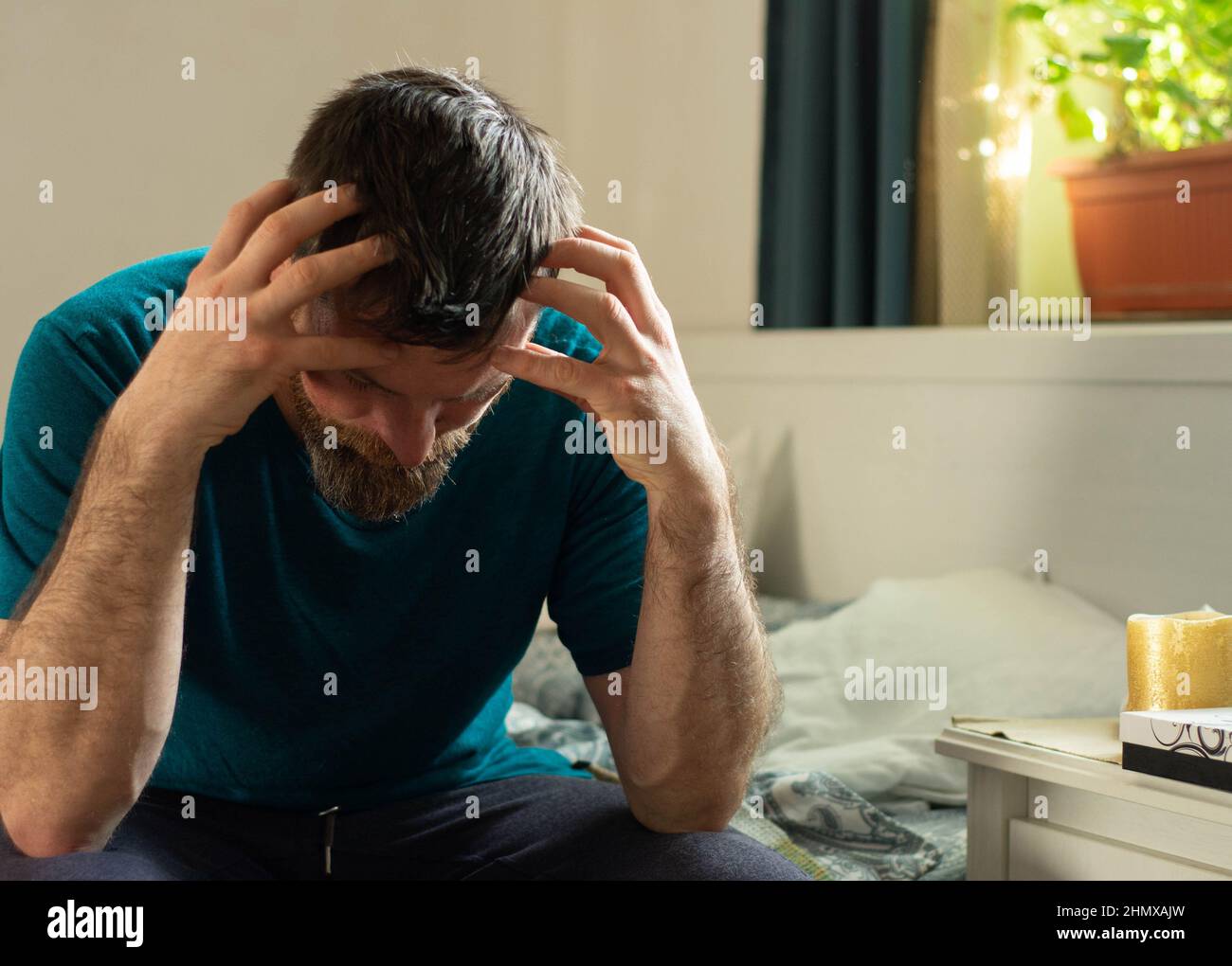 Uomo depresso seduto a letto. Problemi degli uomini. La crisi della condizione umana. Foto Stock