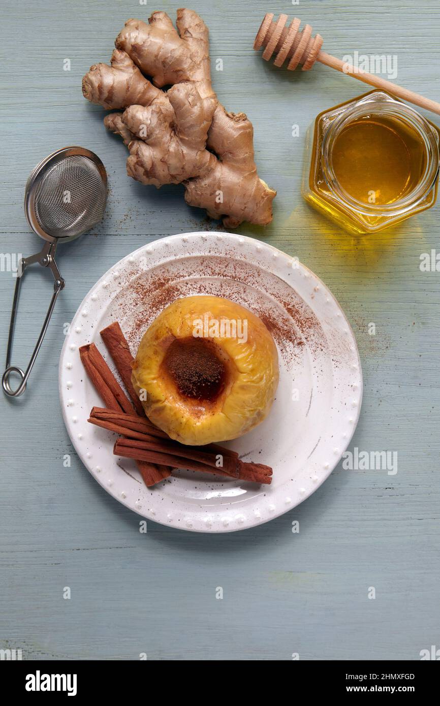 Mela al forno con miele, cannella e zenzero su un tavolo di legno chiaro Foto Stock