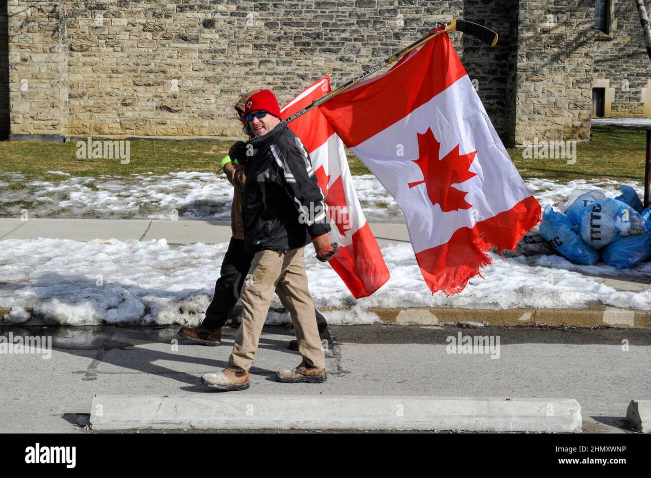 Toronto, Canada. Febbraio 12, 2022. Toronto, Canada. I manifestanti anti anti-mandato, noti anche come Freedom convoy, si radunano al Queen's Park di Toronto per opporsi agli anti-mandati imposti dal governo. Manifestanti che portano la bandiera canadese su un bastone di hockey. Credit: EXImages/Alamy Live News Foto Stock