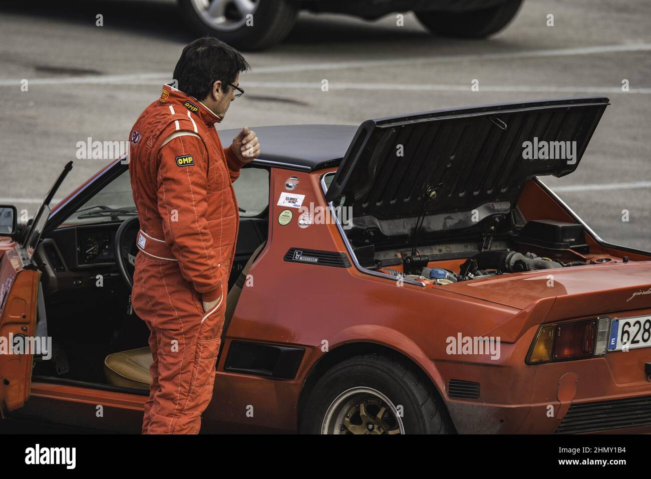 Foto di un pilota vicino ad una Fiat Bertone X1 9 di colore rosso in pista, una rara auto Foto Stock