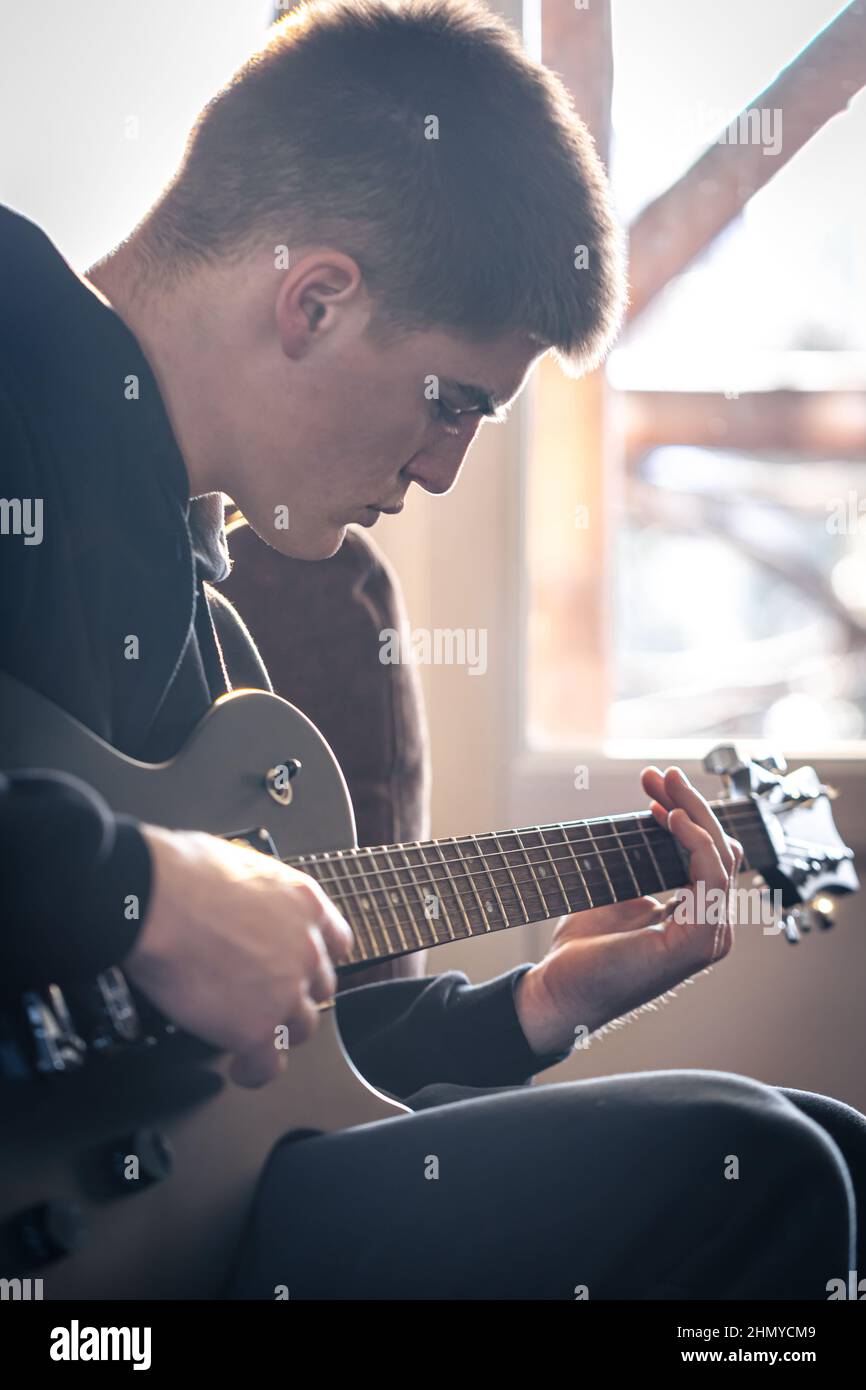 Un giovane suona la chitarra elettrica nella sua stanza. Foto Stock