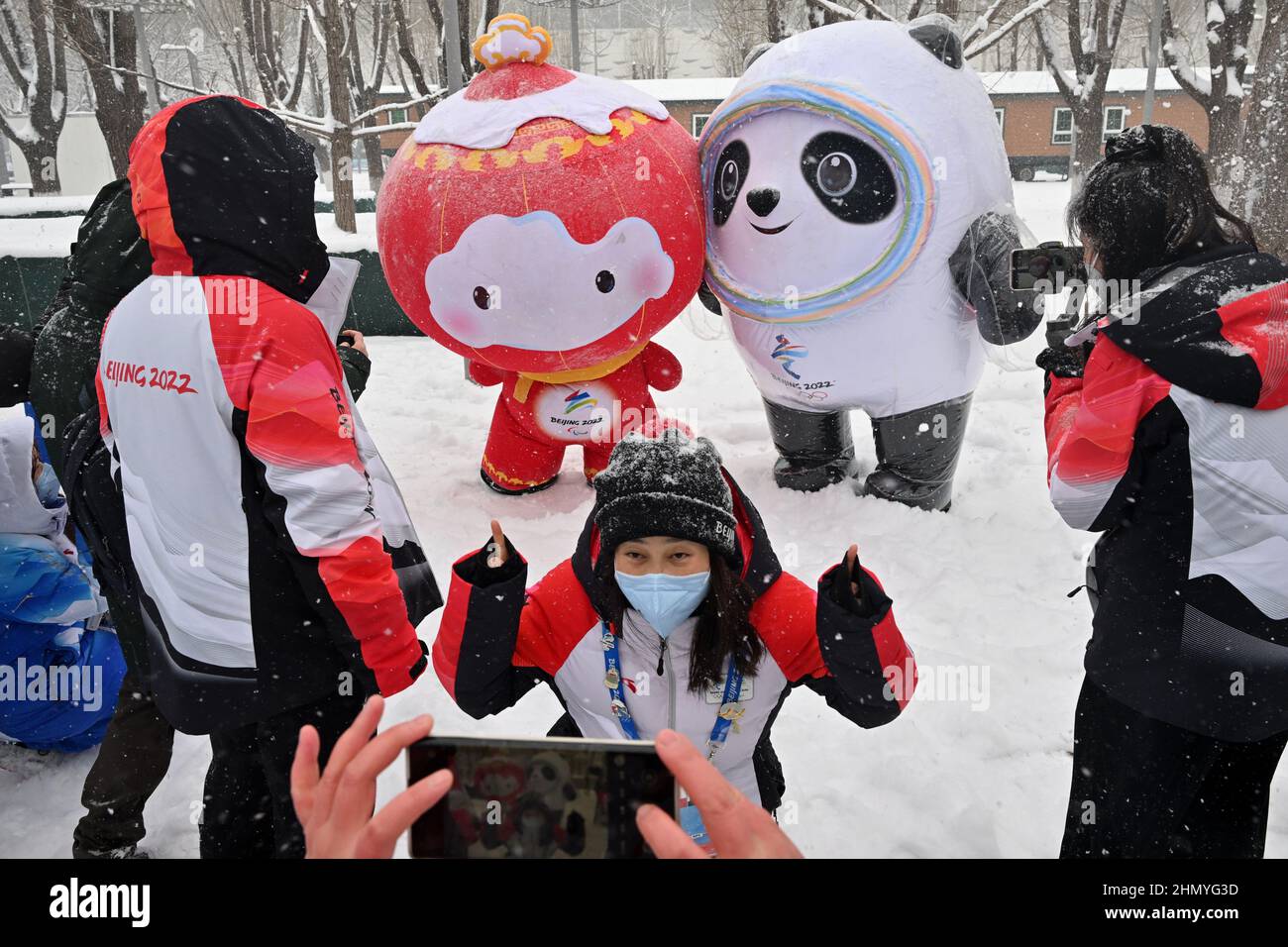 Pechino, Cina. 13th Feb 2022. Olimpiadi, caratteristica, passerby hanno la loro foto scattate di fronte a Shuey Rhon Rhon (l), mascotte ufficiale dei Giochi Paralimpici invernali del 2022, e Bing DWEN DWEN, mascotte ufficiale dei Giochi Olimpici invernali del 2022, nella neve nel parco vicino al centro multimediale. Credit: Peter Kneffel/dpa/Alamy Live News Foto Stock