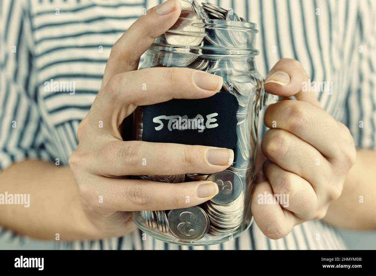 La ragazza tiene il vaso di vetro con le monete. Foto Stock