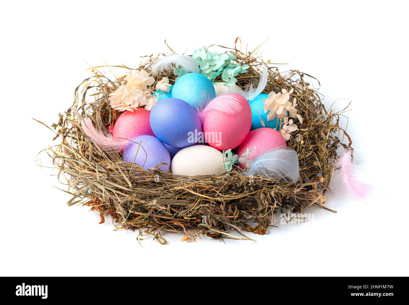 Un grande nido con uova di Pasqua colorate in con piume e fiori isolati su sfondo bianco. Vista laterale, primo piano. Il concetto di Pasqua. Foto Stock