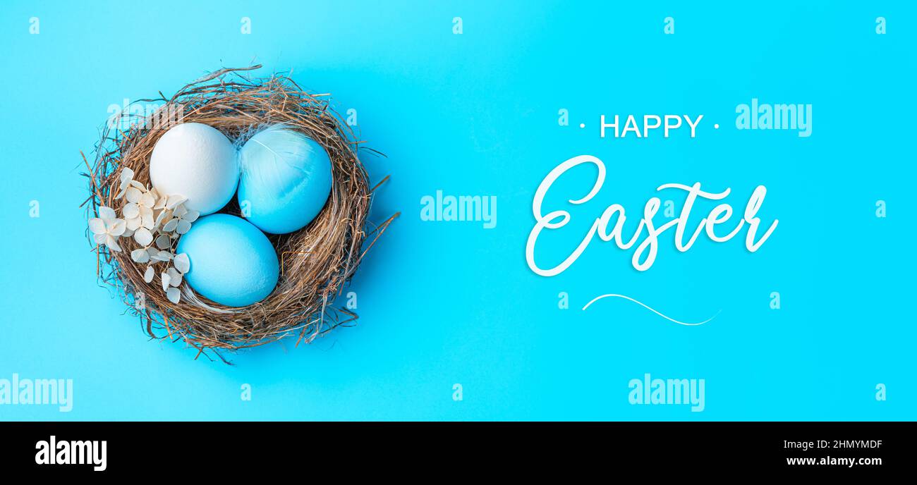 Tre uova di Pasqua in un nido su sfondo blu. Vista dall'alto. Buona Pasqua. Foto Stock