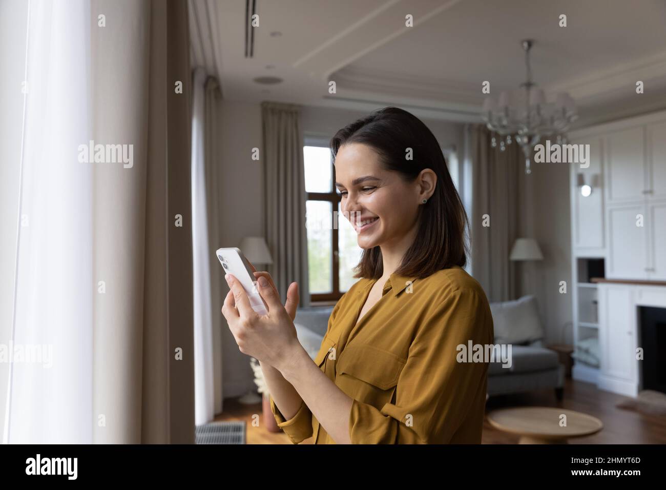 Felice bella giovane donna utilizzando il cellulare a casa. Foto Stock