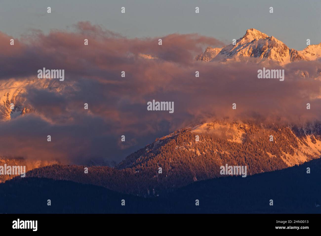 Le nuvole e le montagne innevate di Belledonne si snodano al tramonto Foto Stock