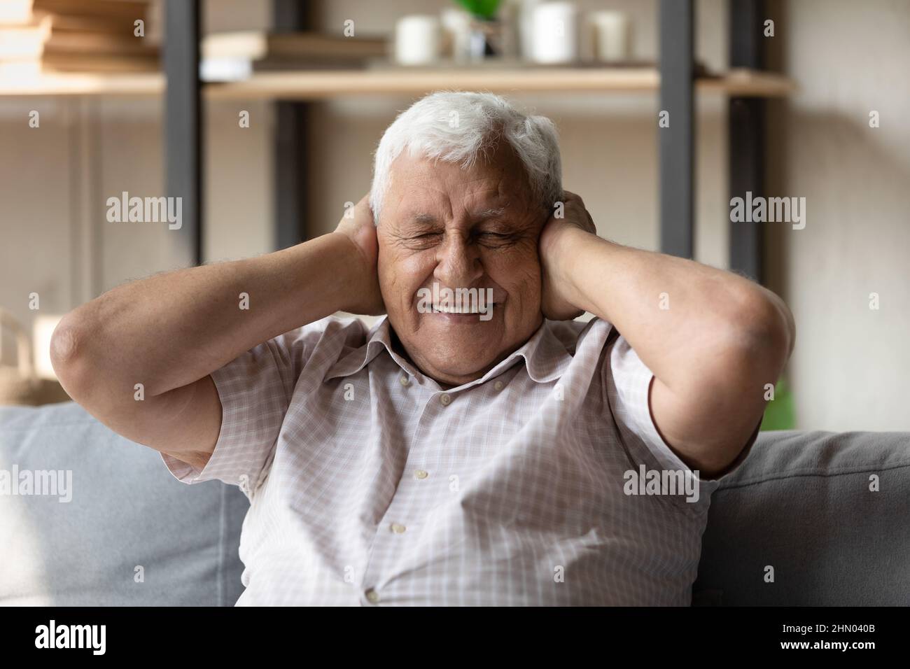 Uomo anziano felice con occhi chiusi che coprono le orecchie Foto Stock