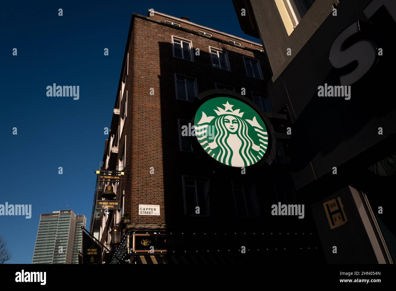 Logo Starbucks che cattura la luce del sole su Tottenham Court Road in una fredda giornata di inverni a Londra nel Regno Unito Foto Stock