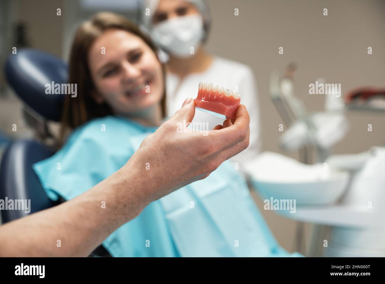 Il dentista mostra al paziente un modello della mandibola con un tutore in silicone Foto Stock