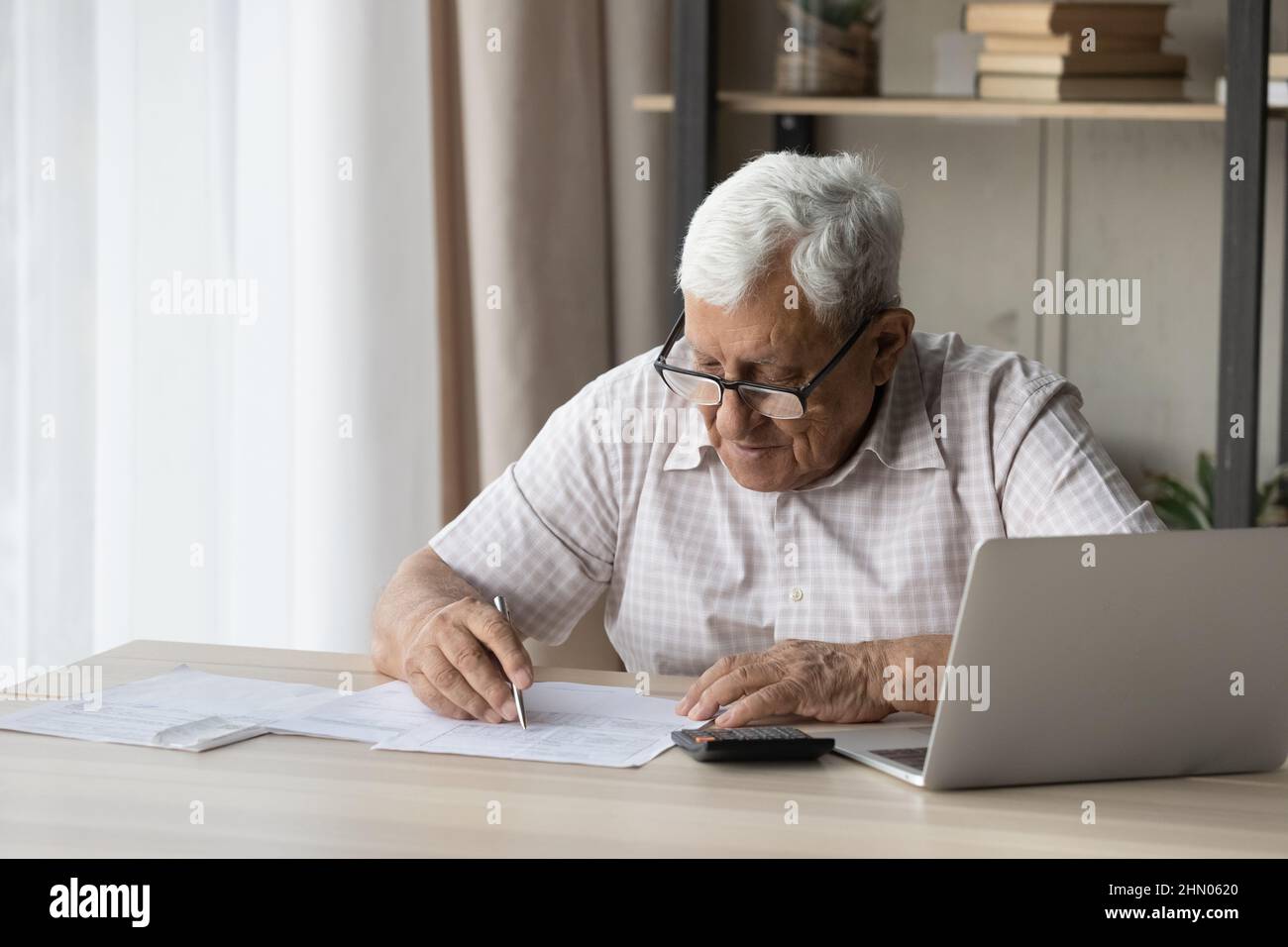 Anziano 80s uomo anziano in occhiali che fanno la documentazione a casa Foto Stock