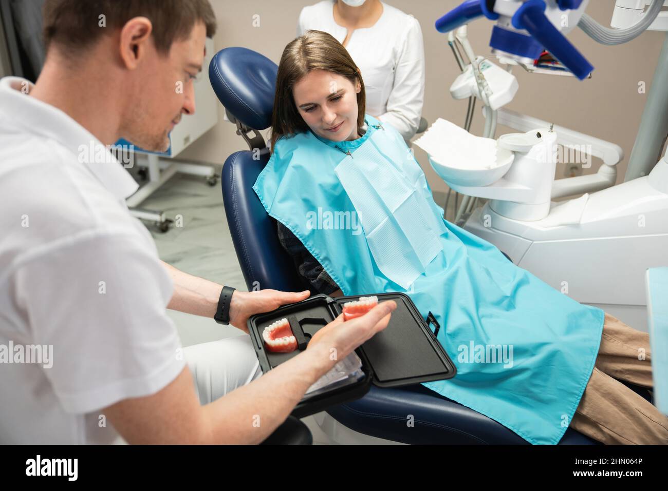 Il dentista mostra al paziente un modello della mandibola con un tutore in silicone Foto Stock
