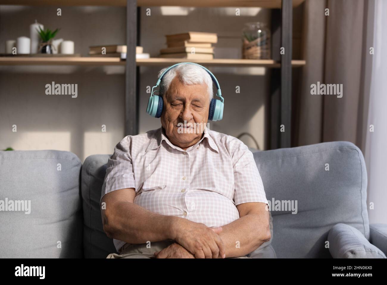 Vecchio stanco che ascolta la musica dalle grandi cuffie wireless Foto Stock