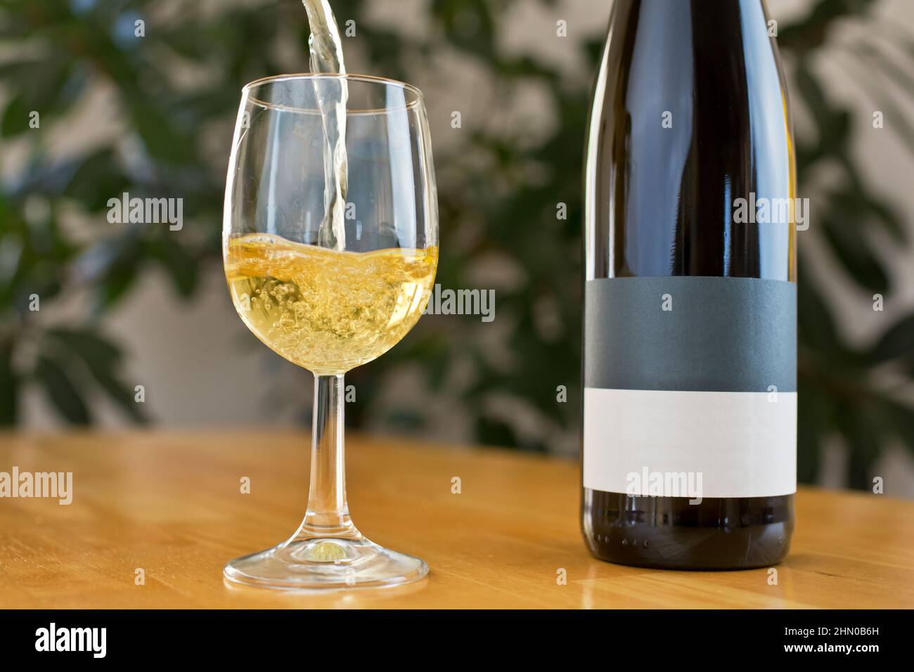 Versare il vino bianco in un bicchiere con la bottiglia a parte Foto Stock