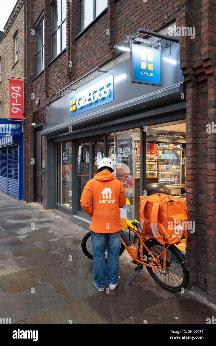 Una persona di consegna di Just Eat si prepara ad entrare in Greggs per ritirare un ordine per la consegna. Preso presto la Domenica mattina a Lower Marsh, Waterloo Londra Foto Stock